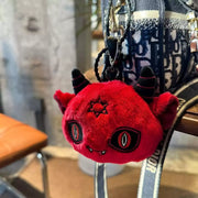 Dark Envoy Plush Charm Buu Evil keychain with red plush, horns, and sleepy eyes hanging from a bag.