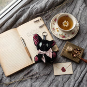 Listening black cat plush toy beside a cup of tea and an open notebook, showcasing its charming details.