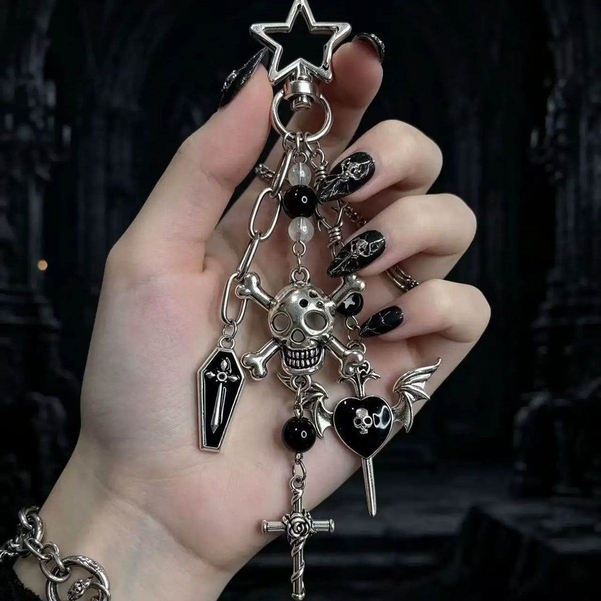 Gothic Skull and Cross Bag Charm featuring skull, coffin, cross, and heart charms on a hand.