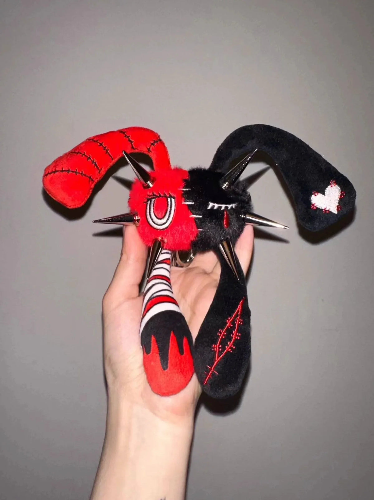 Rivet Punk Rabbit plush charm with studs, red and black color, and four distinctive ears held in hand.