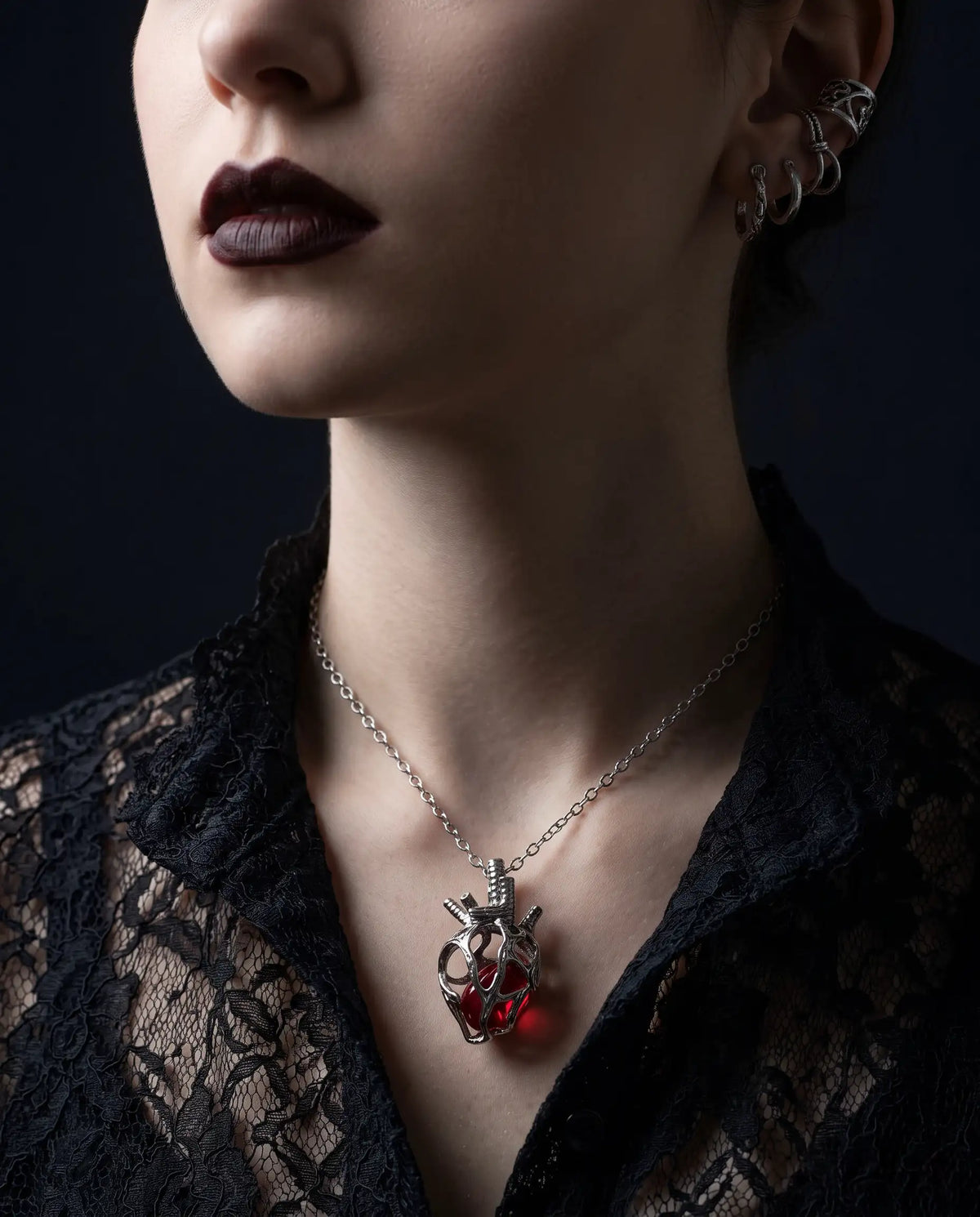 A close-up of a person wearing the Soul Resonance Gothic Heart Necklace with a red glass core, styled in vintage-gothic fashion.