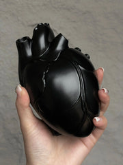 A hand holding a Vintage Heart Trinket Box shaped like an anatomical heart in a matte black finish.
