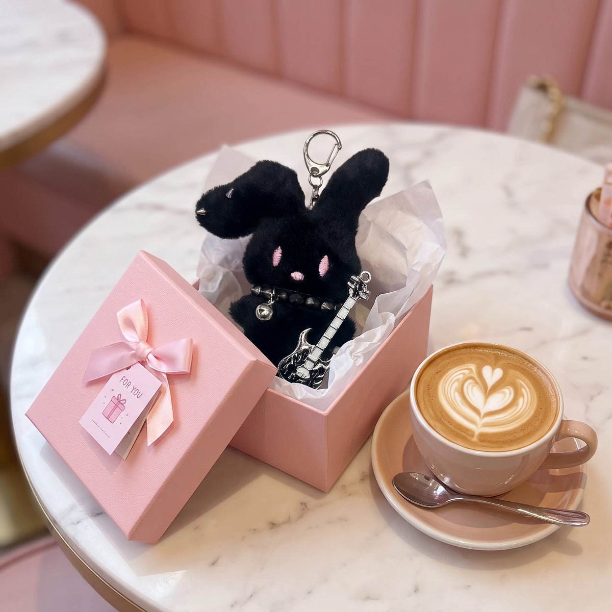 Guitarist Bunny Plush Charm in a gift box with a guitar, alongside a coffee cup on a marble table.