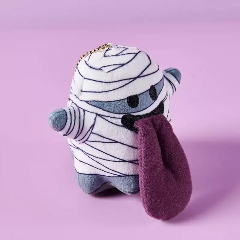 Monster Crew Plush Bag Charm featuring a cute mummy design with sleepy eyes and a purple tongue, perfect for Halloween.
