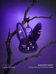 Cuddly bunny plush keychain hanging on a branch with a purple background, featuring a stylish and unique design.