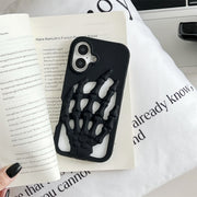 3D Skeleton Hand Gothic Phone Cover displayed on a table with a book and pillow in the background.