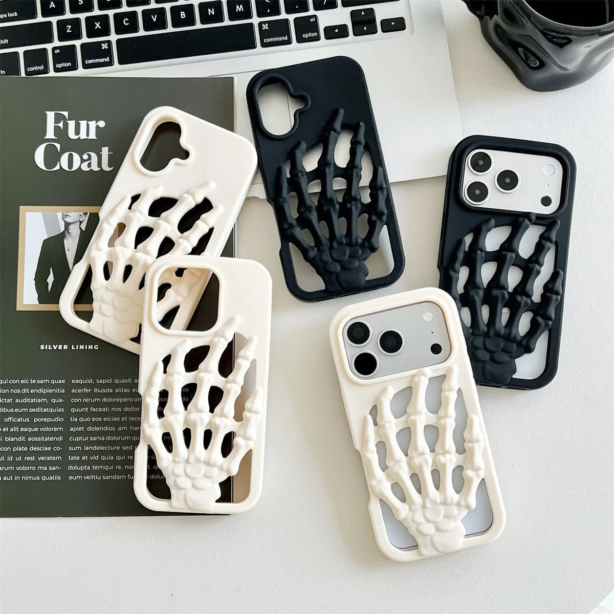 3D Skeleton Hand Gothic Phone Cover displayed on a desk with a laptop and magazine.
