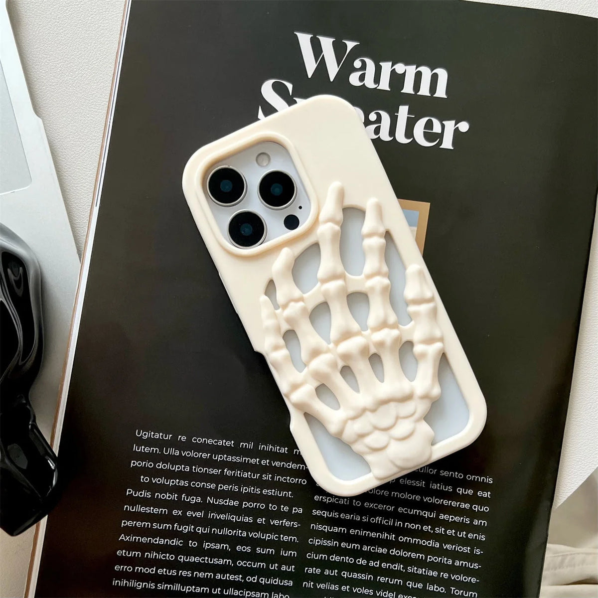 3D Skeleton Hand Gothic Phone Cover displayed on a magazine, featuring a sculpted skeletal hand design.
