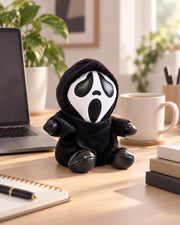 Gloomy Oddboo Buu Evil plush toy sitting on desk with laptop and coffee mug.