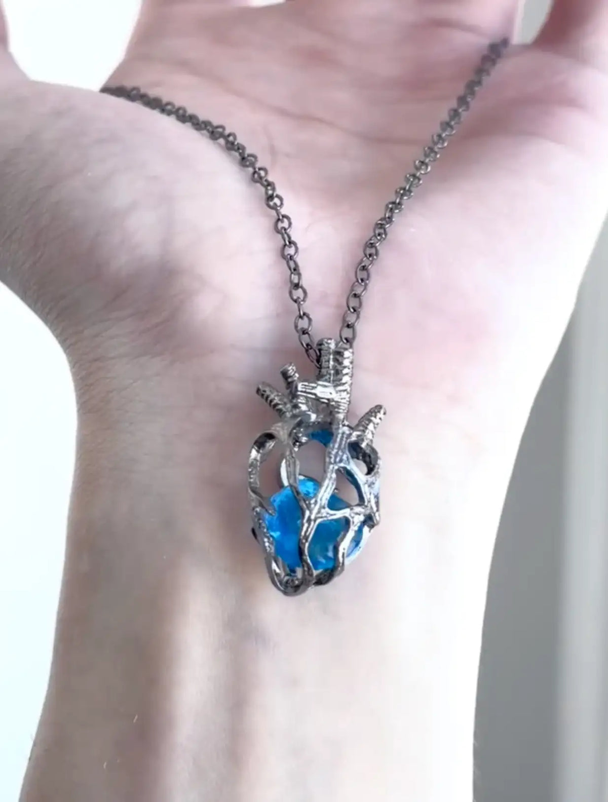 Soul Resonance Gothic Heart Necklace featuring a blue glass heart in intricate filigree on a chain.
