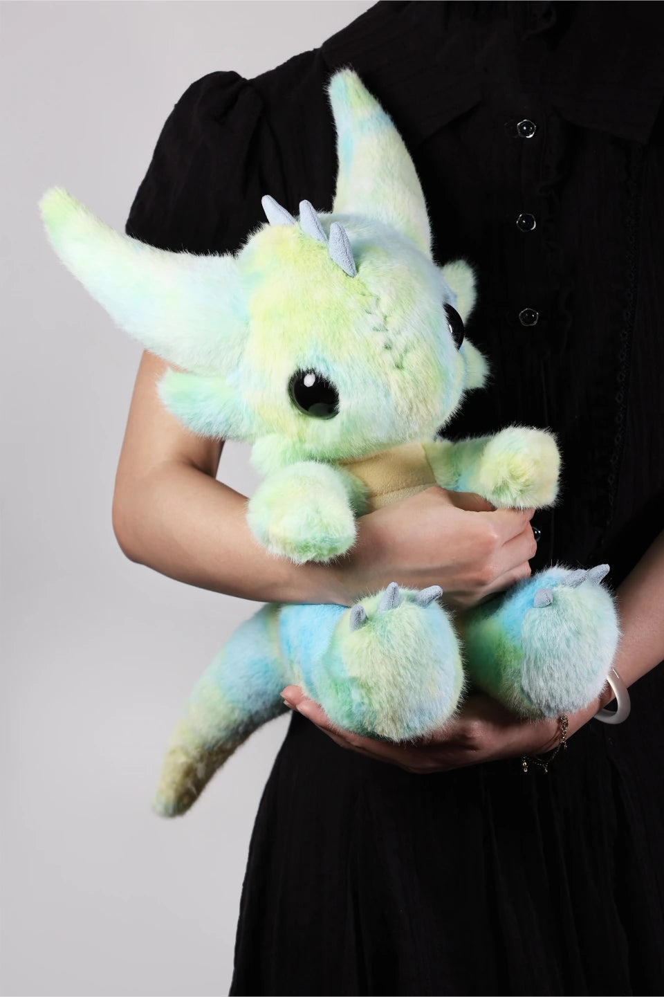 A person holding a stuffed dragon Boo plush toy, showcasing its vibrant colors and cuddly features.