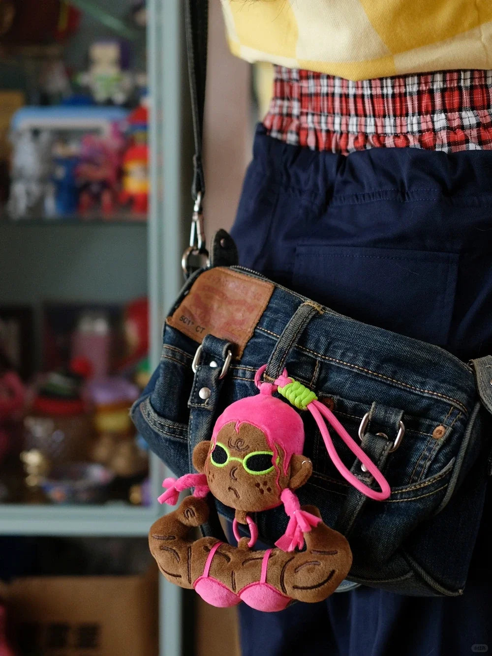 Buu Evil plush bag charm hanging from a denim bag, showcasing its muscular design and vibrant colors.