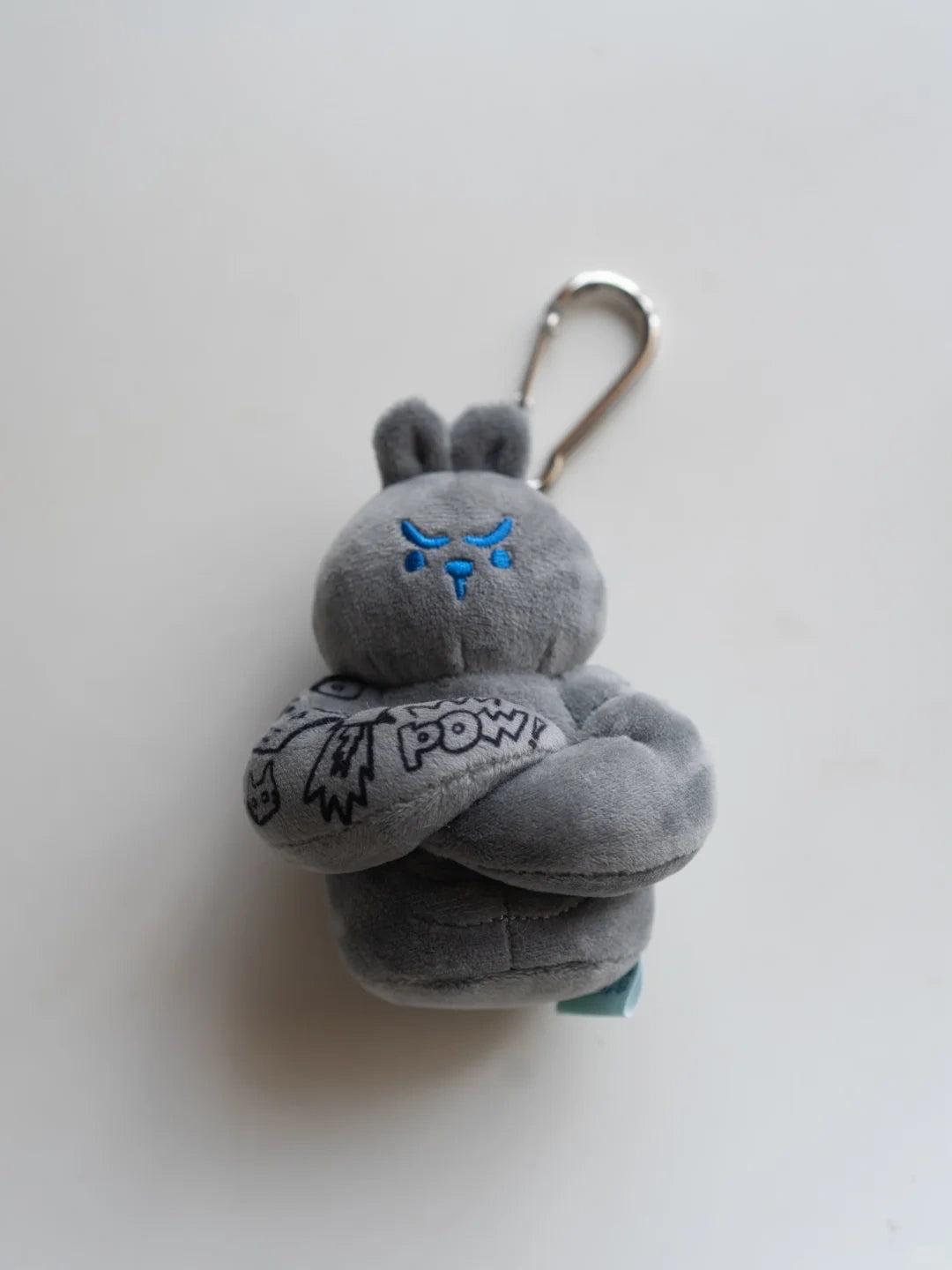 Bunny plush bag charm featuring a gray bunny with arms crossed and a clip attachment for easy carrying.