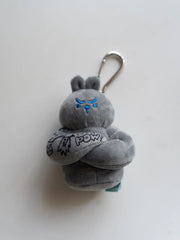 Bunny plush bag charm featuring a gray bunny with arms crossed and a clip attachment for easy carrying.