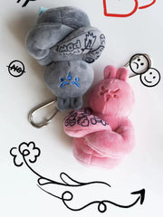 Grey and pink muscle bunny plush keychains with tattoo sleeves and doodle background, kawaii fitness bag charms
