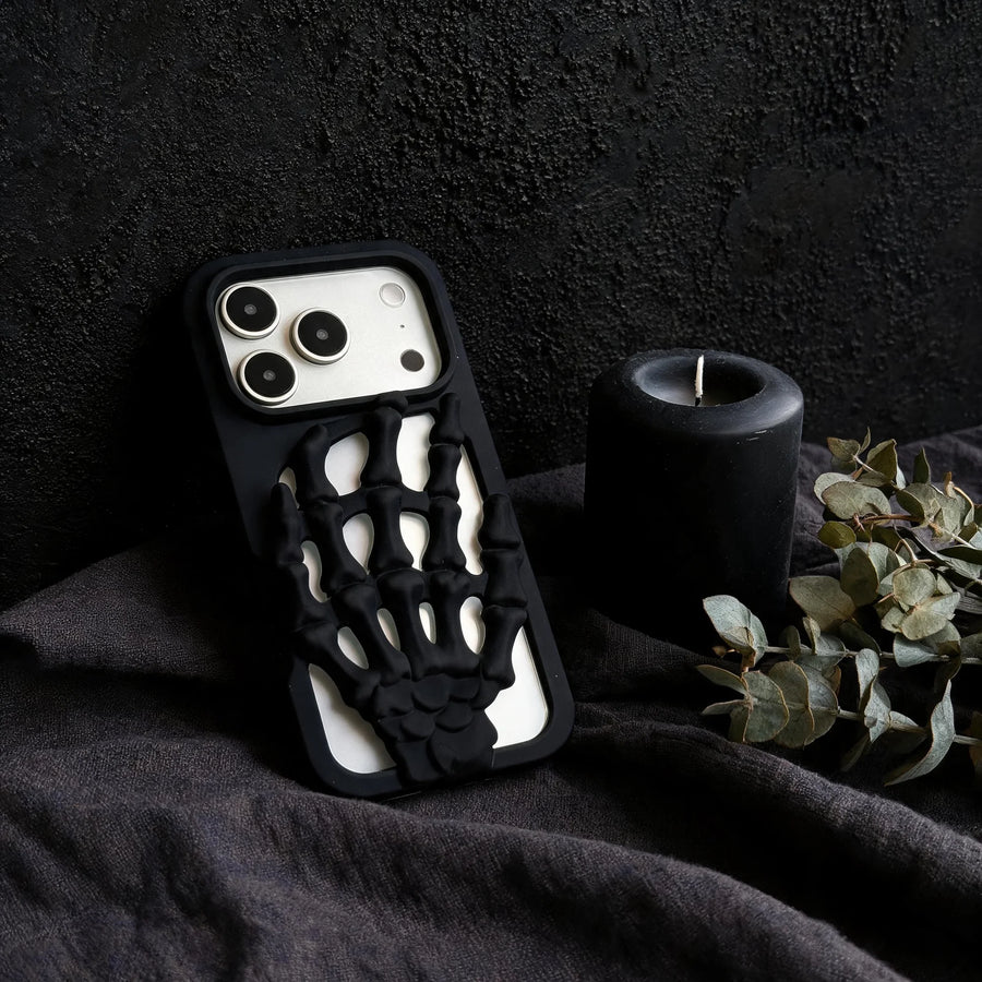 3D Skeleton Hand Gothic Phone Cover with a sculpted skeleton hand design, resting next to a candle and greenery.