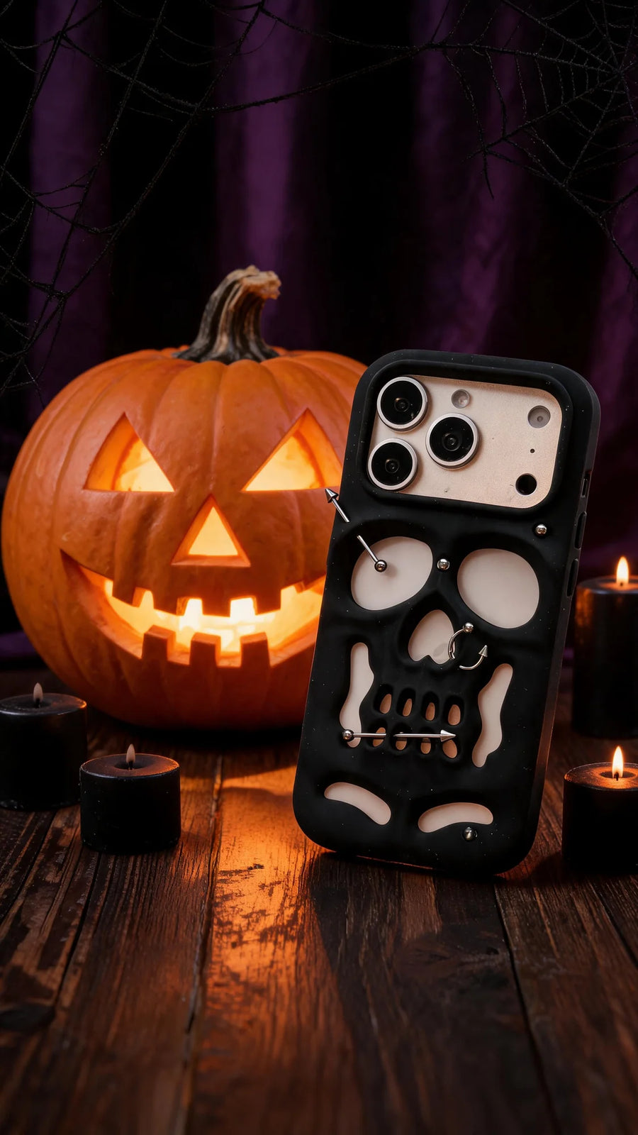 Buu Evil:Gothic punk skull studded iPhone case displayed next to a carved pumpkin and candles on a wooden surface.
