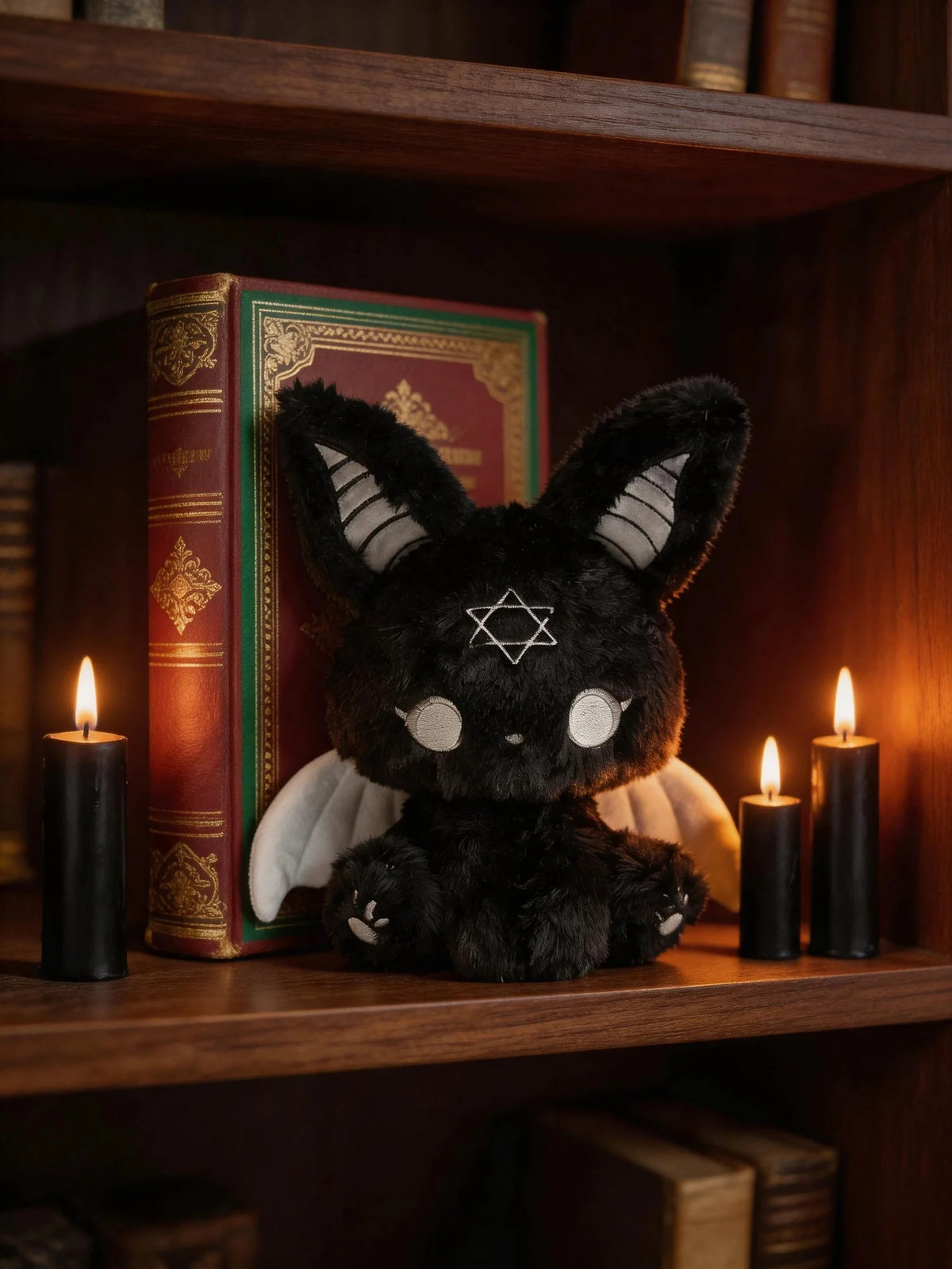 Dark Envoy Gothic Cute Plush Doll - Buu Evil sitting on a shelf with candles and a book, showcasing its charming goth aesthetic.