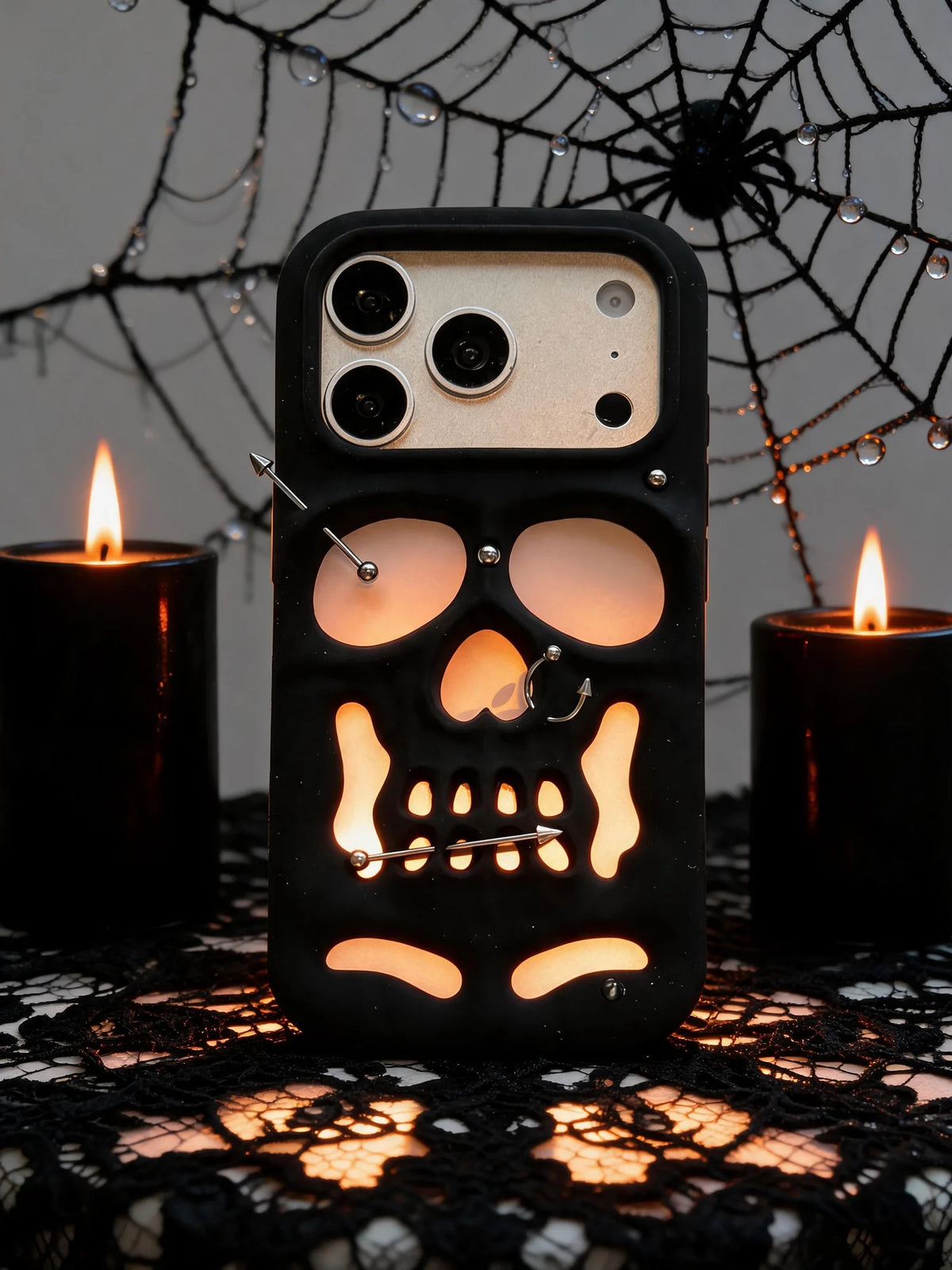 Buu Evil:Gothic punk skull studded iPhone case displayed with candles and spiderweb decor.