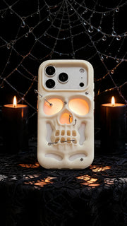 Buu Evil:Gothic punk skull studded iPhone case surrounded by candles and spiderwebs, showcasing its unique hollow skull design.