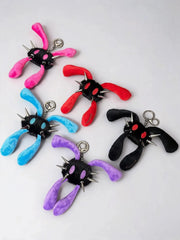 Five plush monster keychains with long fuzzy bunny-like legs and metal spikes, shown in pink, red, blue, purple, and black on a light gray background.