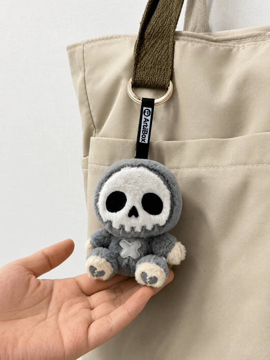 Little Angu skull plush charm clipped onto canvas tote pocket