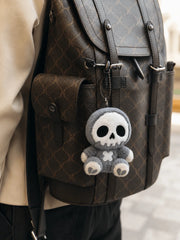 Little Angu plush charm hanging from a bag, showcasing its cute skull design and stitched features.